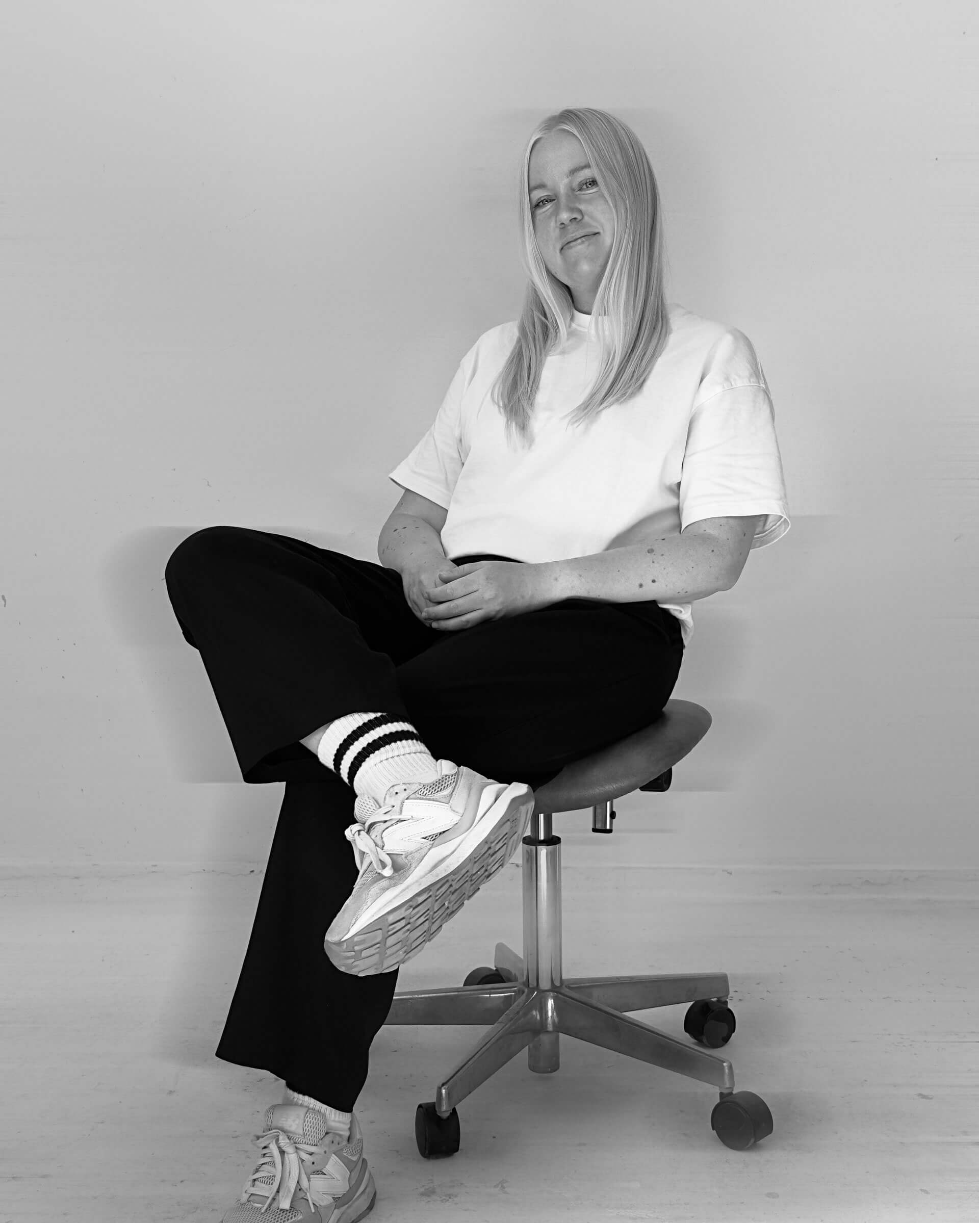 black and white portrait of Creative Director Camilla Wedege sitting on an office chair