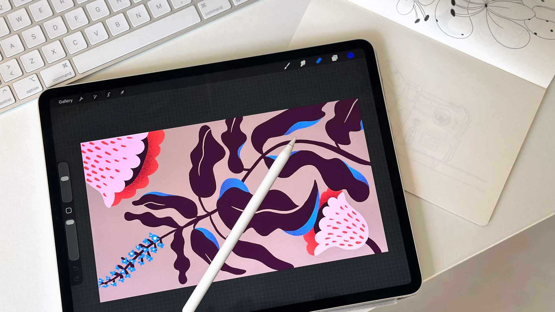 Ipad with procreate illustration on a desk with a keyboard and a sketchbook